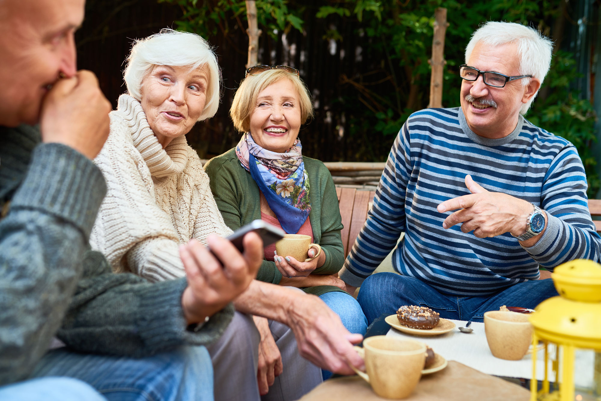 Eldre mennesker sitter ute og drikker kaffe. Foto