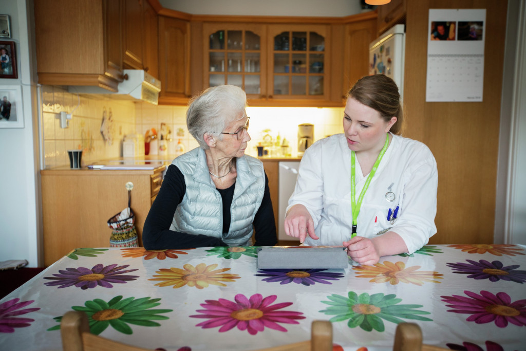 Eldre damer snakker med pleier. Foto