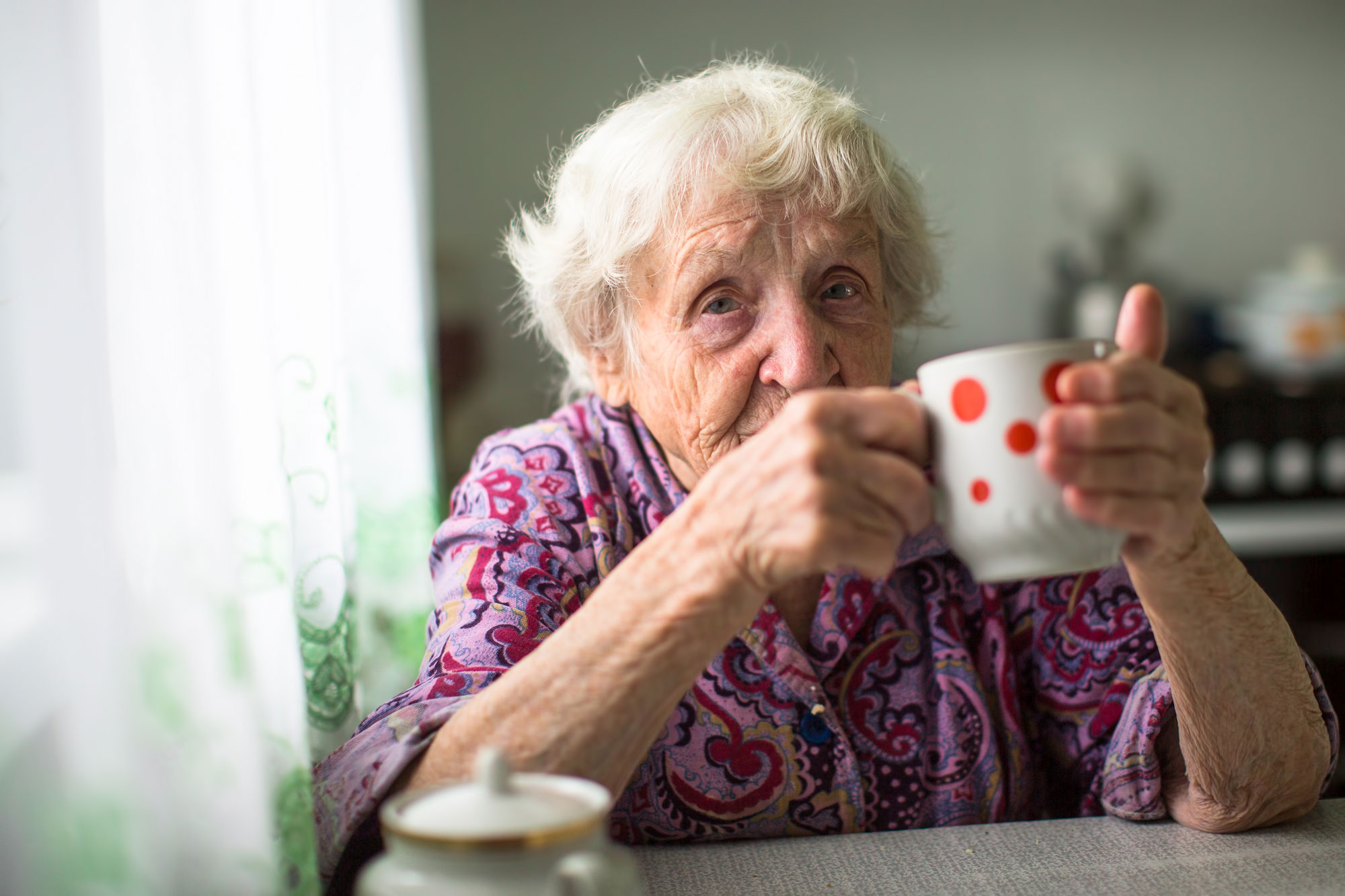 Eldre kvinne med kopp. Foto.