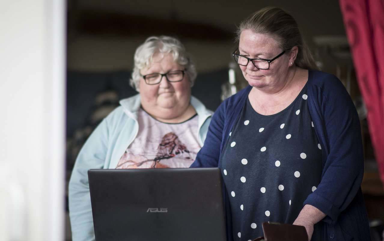Kvinne og person med utviklingshemming ser på skjerm. Foto.