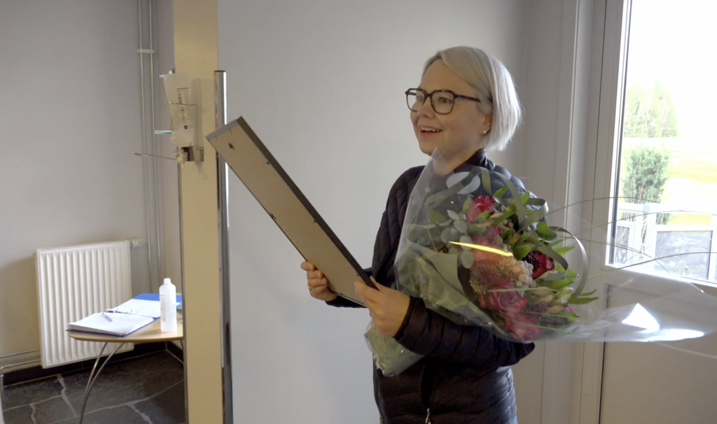 Kvinne med diplom. Foto fra video.