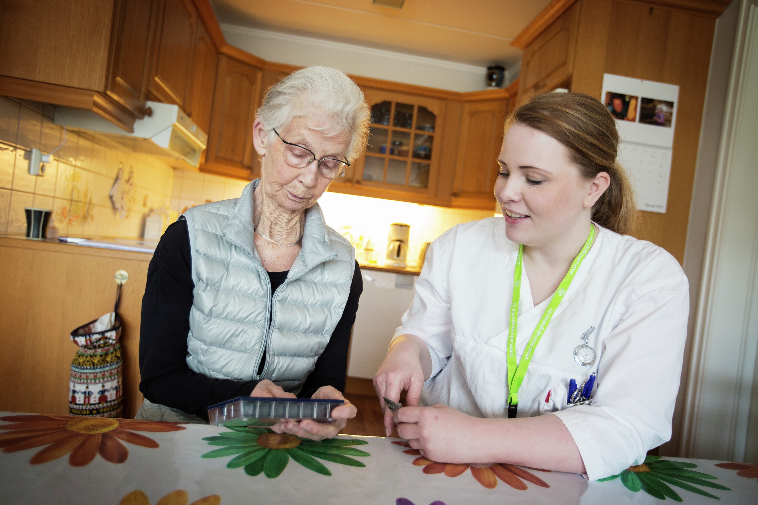 Pleier hjelper eldre kvinne med medisiner. Foto