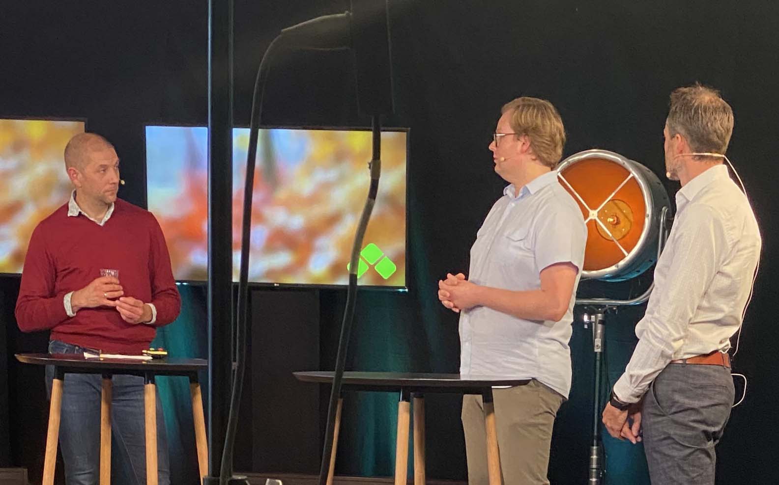 Tre menn diskuterer i studio. Foto.
