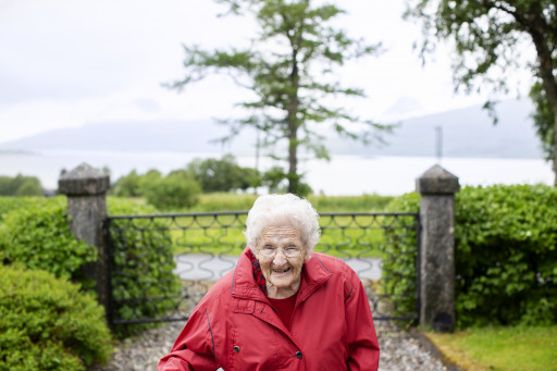 Eldre smilende kvinne kommer gående mot oss