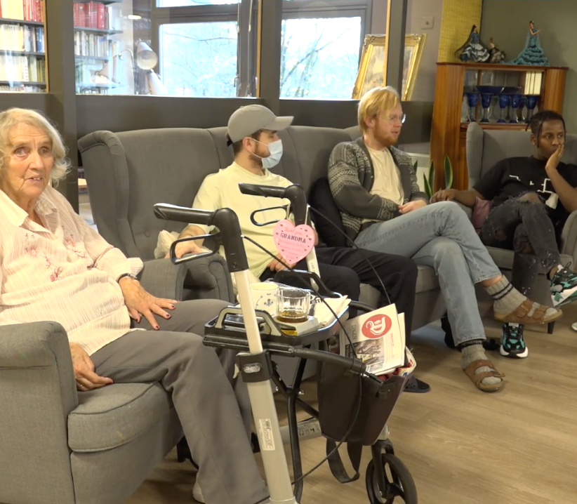 Studenter og eldre sitter sammen. Skjermdump fra video om Paulus sykehjem