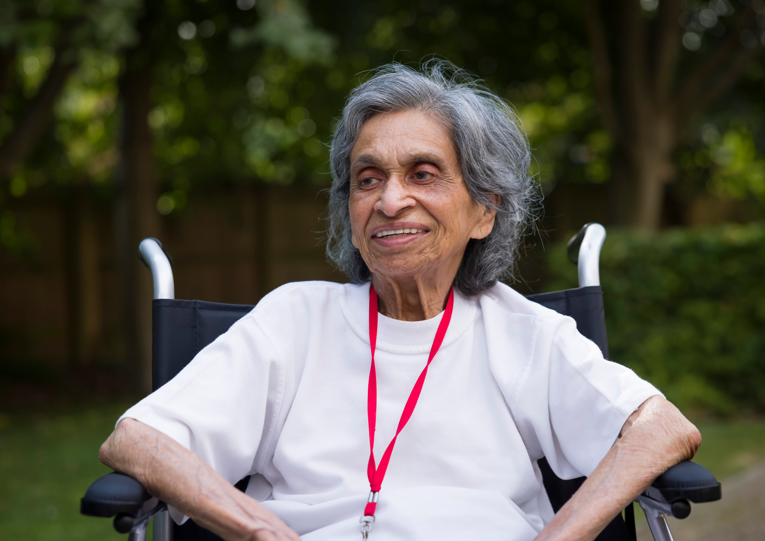 Eldre minoritetskvinne i rullestol smiler