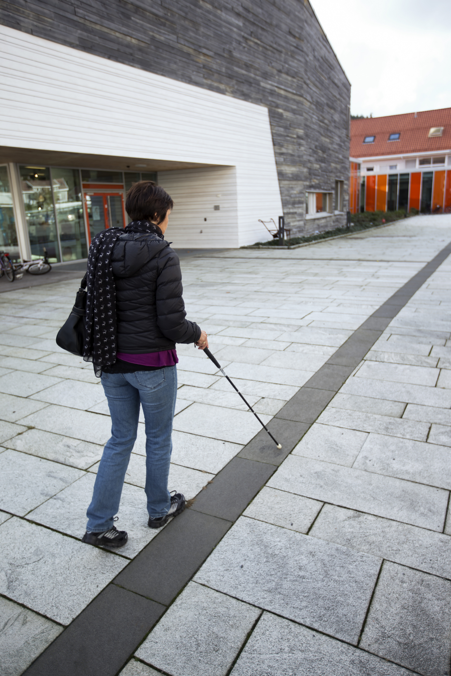 Blind kvinne med blindestokk er ute og går.