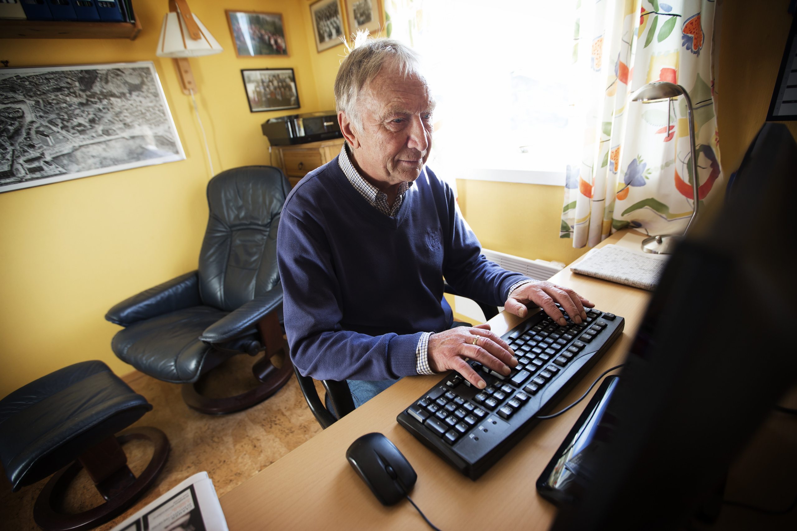 Eldre mann foran PC-skjerm på hjemmekontor. Foto.