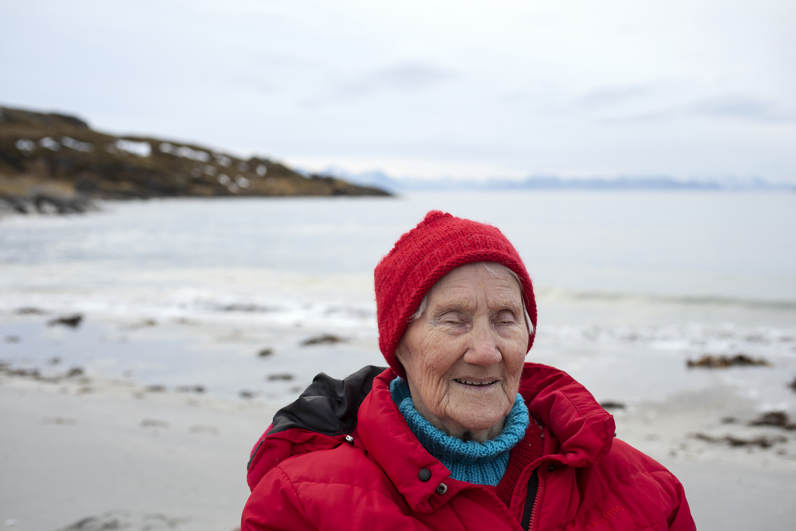 Eldre kvinne med øynene lukket - i bakgrunnen havet