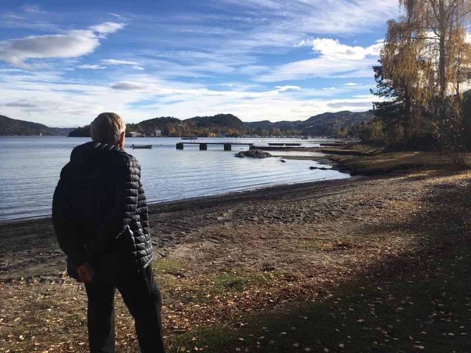 Bilde av en mann som står på en strand, med ryggen til kameraet.