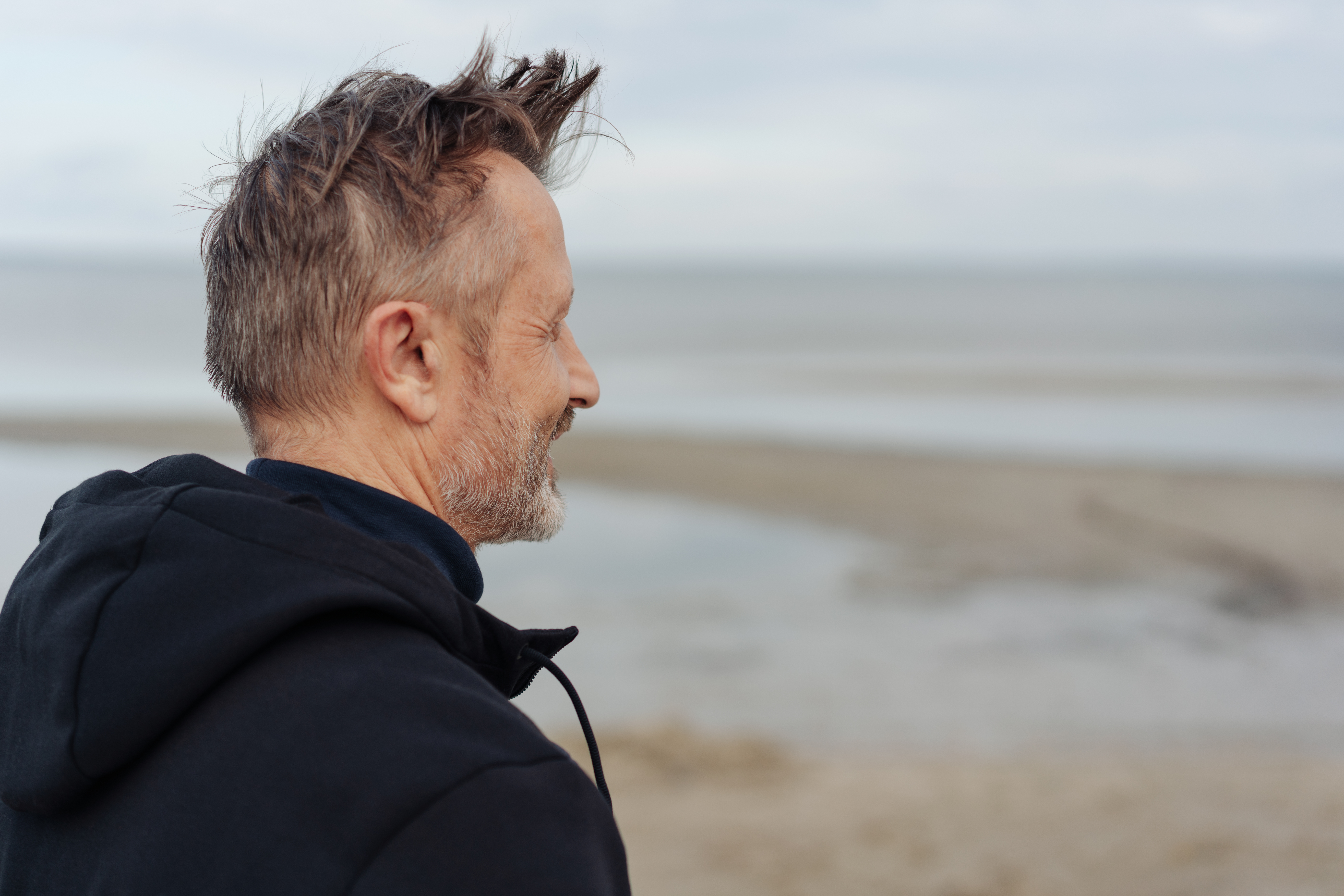 Mann står på stranden og ser utover havet