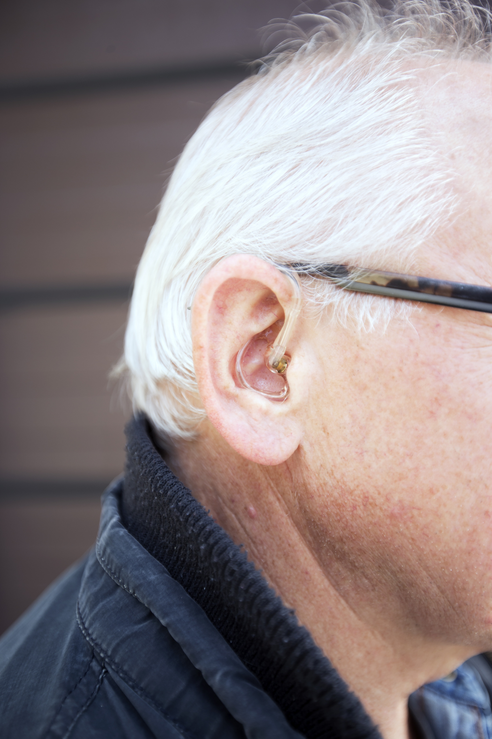 Mann med høreapparat i ene øret og briller. Foto