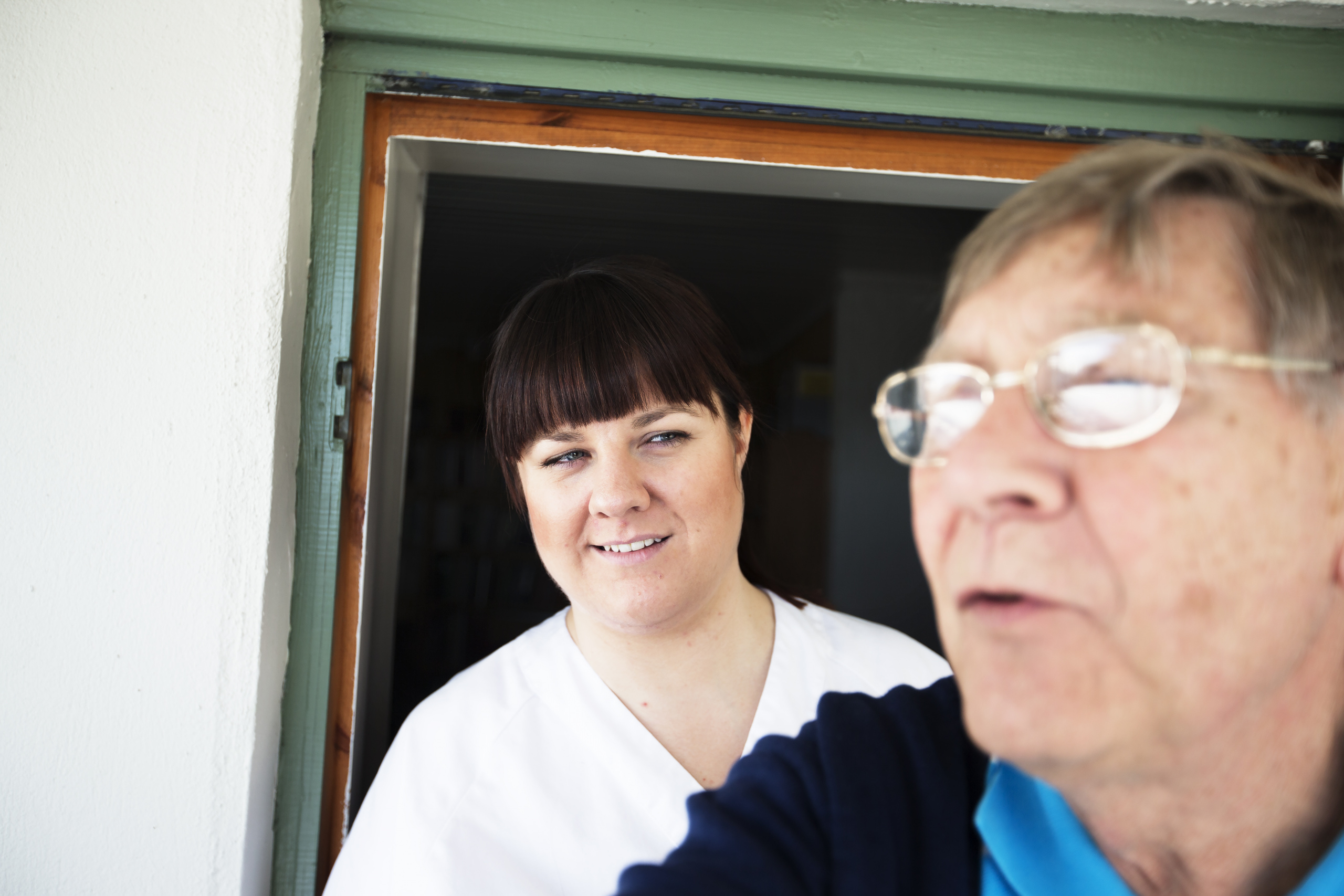 Kvinnelig helsepersonell med eldre mann i forgrunnen. Foto.