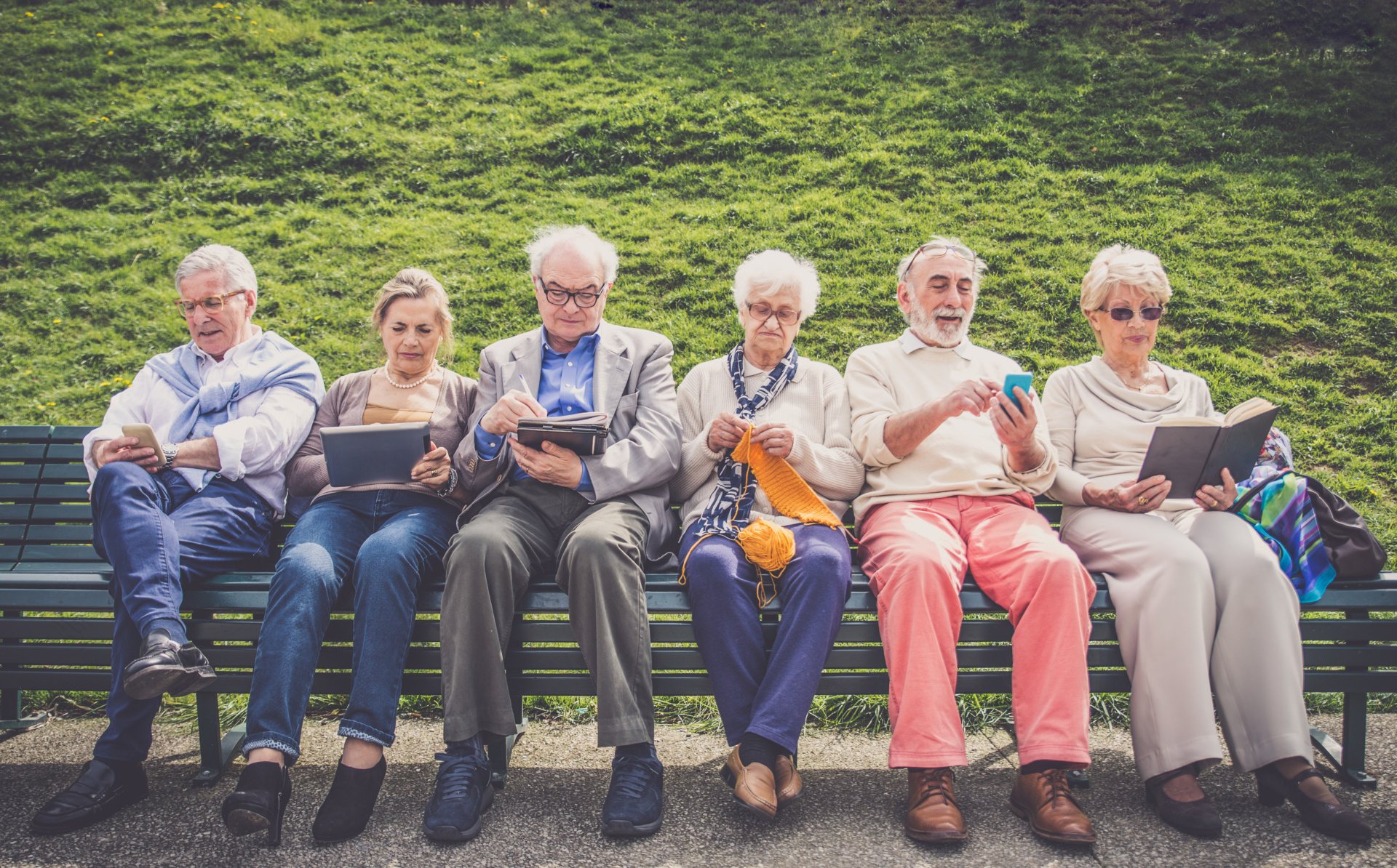 Mange eldre mennesker sitter på en benk. Foto