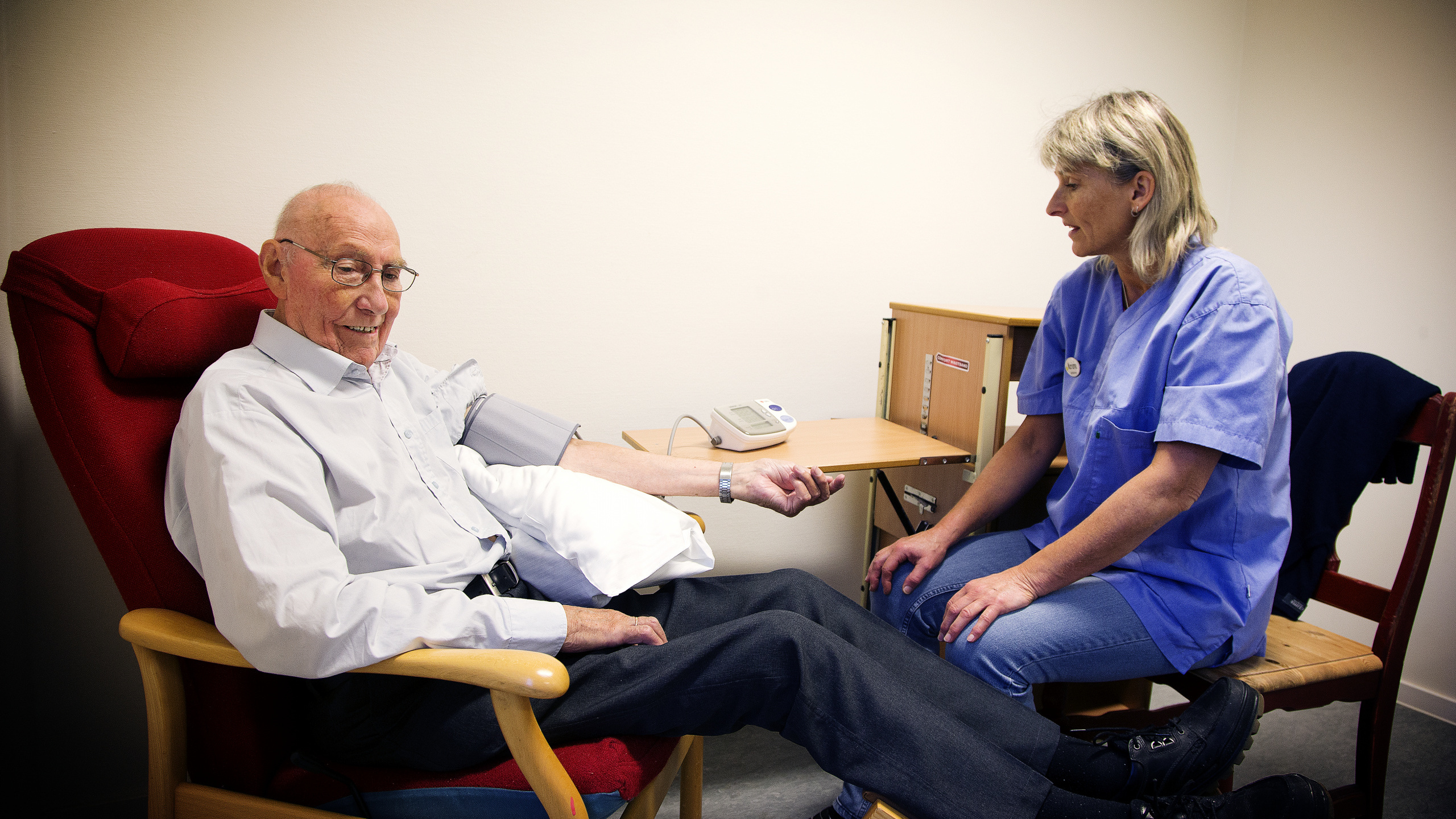 Eldre mann får målt blodtrykk av helsepersonell. Foto