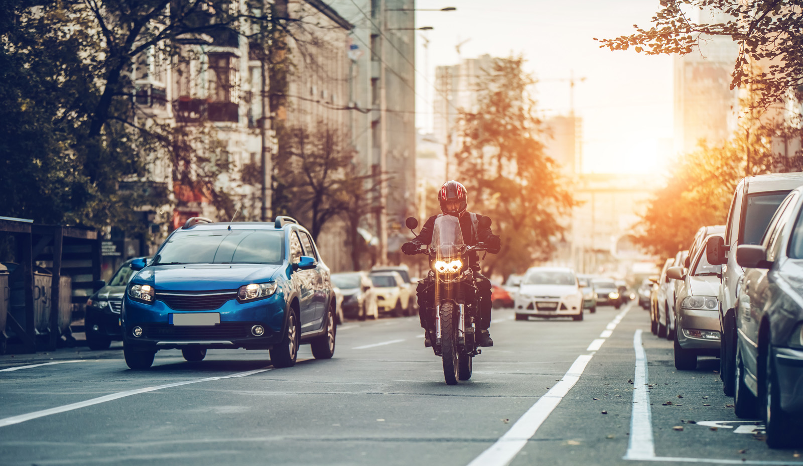 Bybilde med bil og motorsykkel i solnedgang. Foto