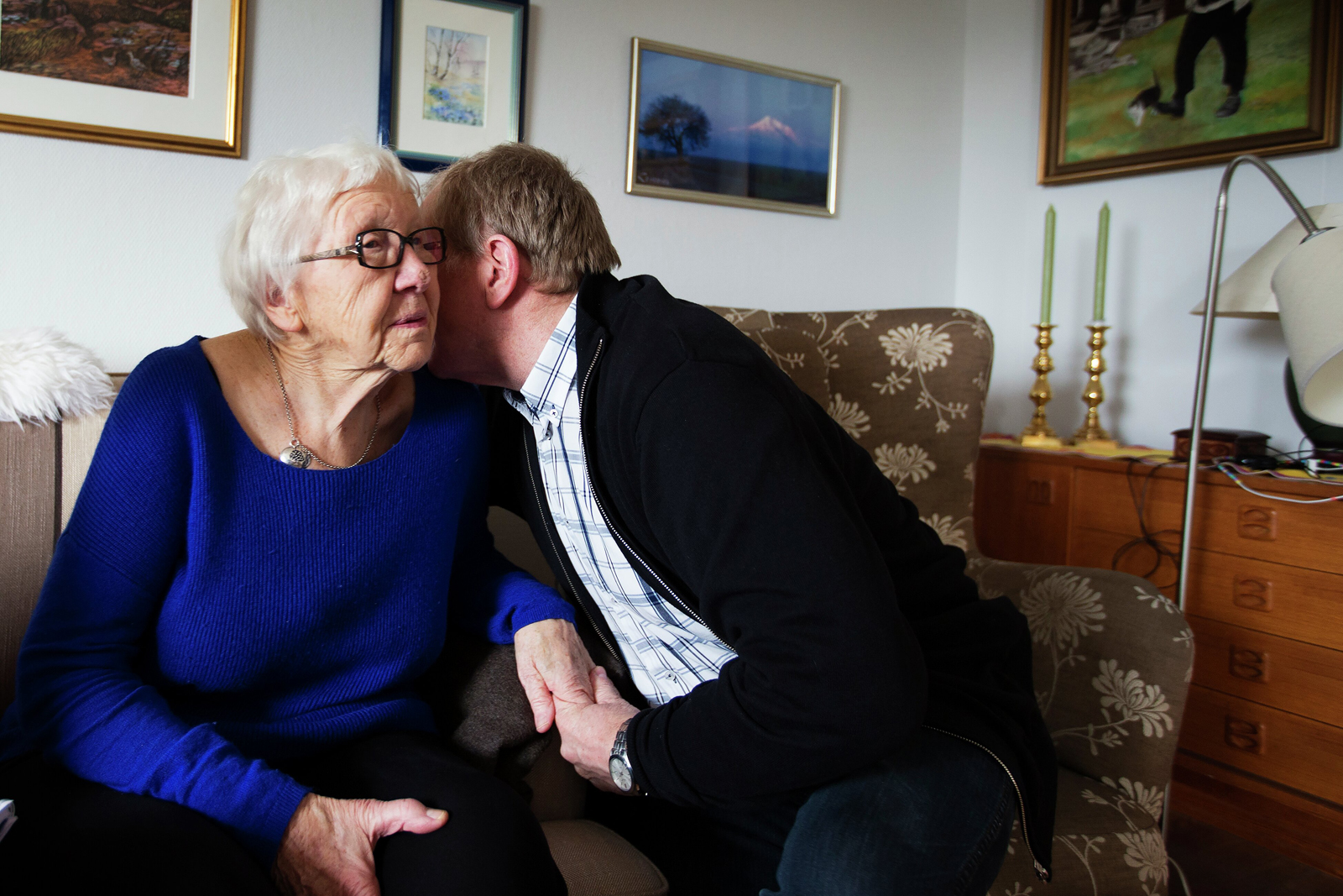 Eldre kvinne får klem av mann. Foto