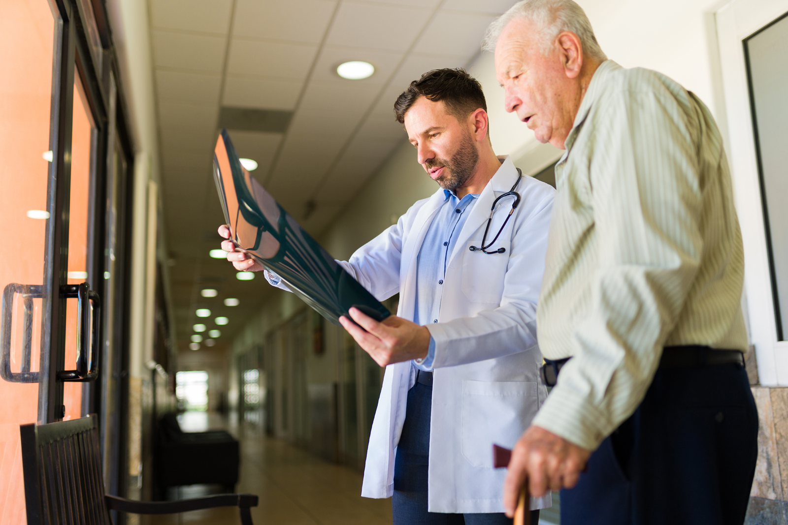 Mannlig helsepersonell og eldre mann ser på røntgenbilde. Foto