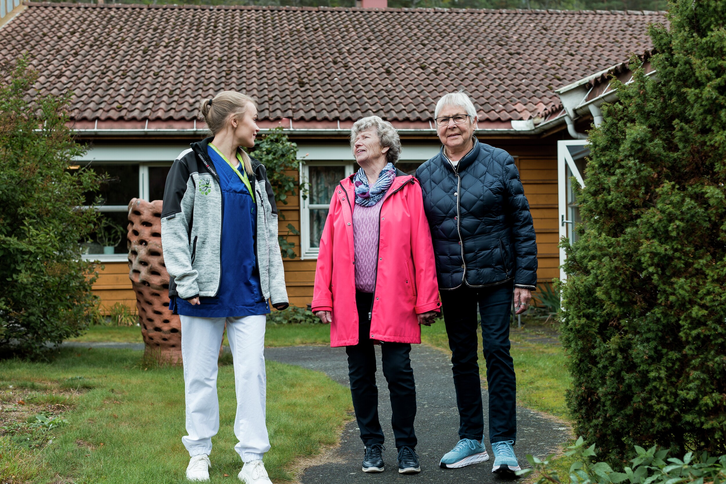 Eldre og helsepersonell utenfor bolig. Foto.