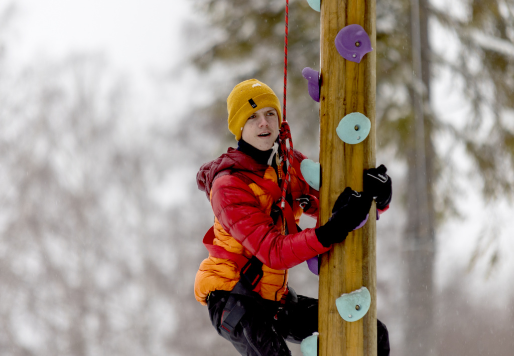 Gutt klatrer i stolpe.