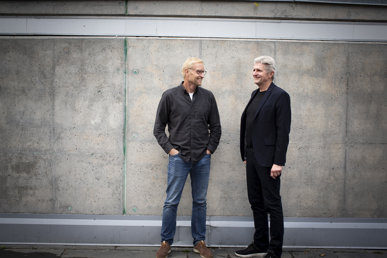 Programleder og fast deltaker i Aldring og helse-podden foran murvegg. Foto