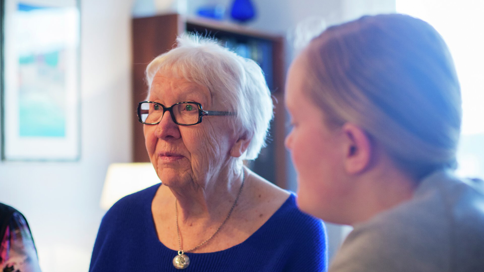 Eldre kvinne med yngre kvinne foran (ute av fokus). Foto
