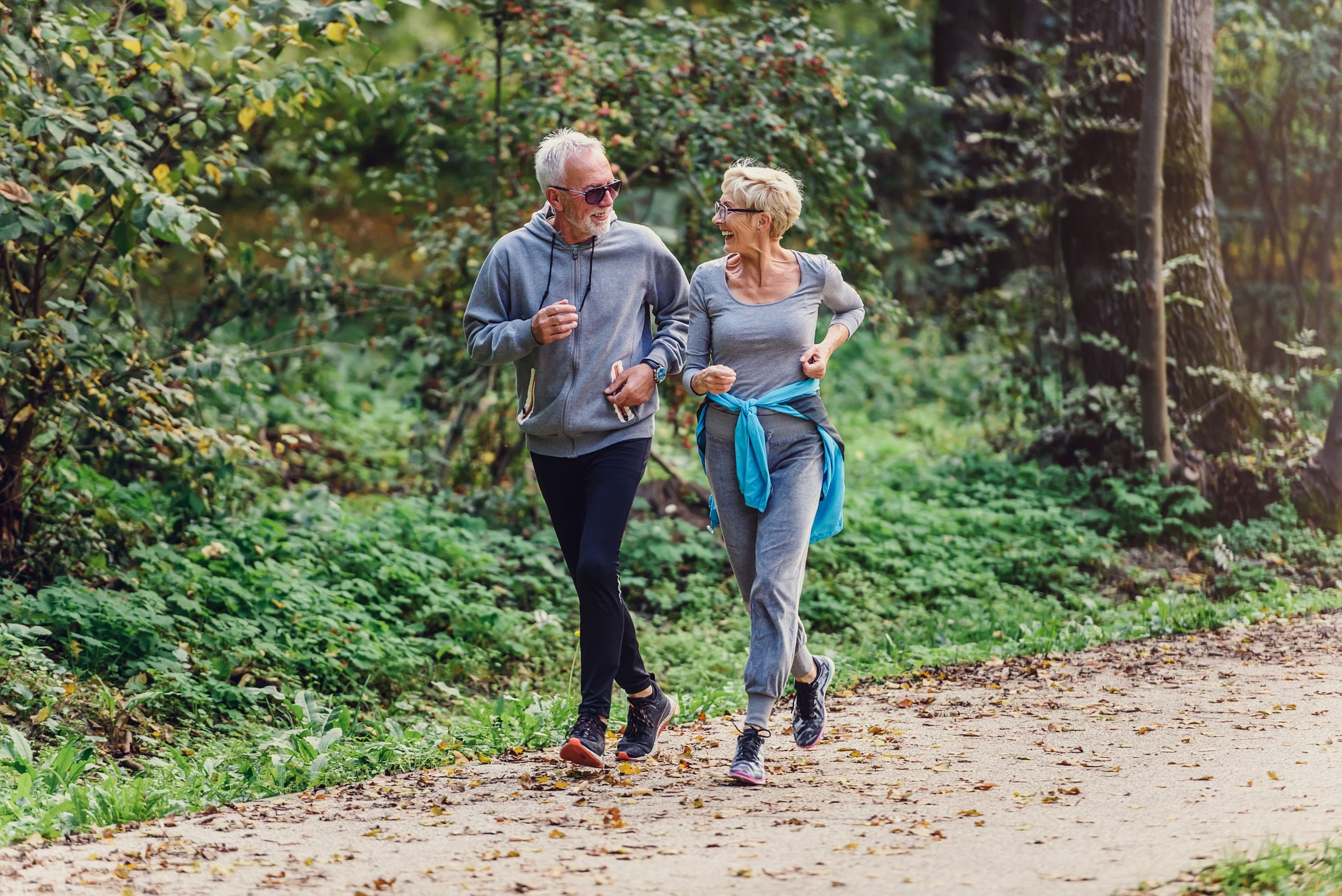 To eldre som jogger u skogen. Foto.