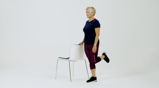 Eldre kvinne trener ved stol. Skjermdump fra treningsfilm