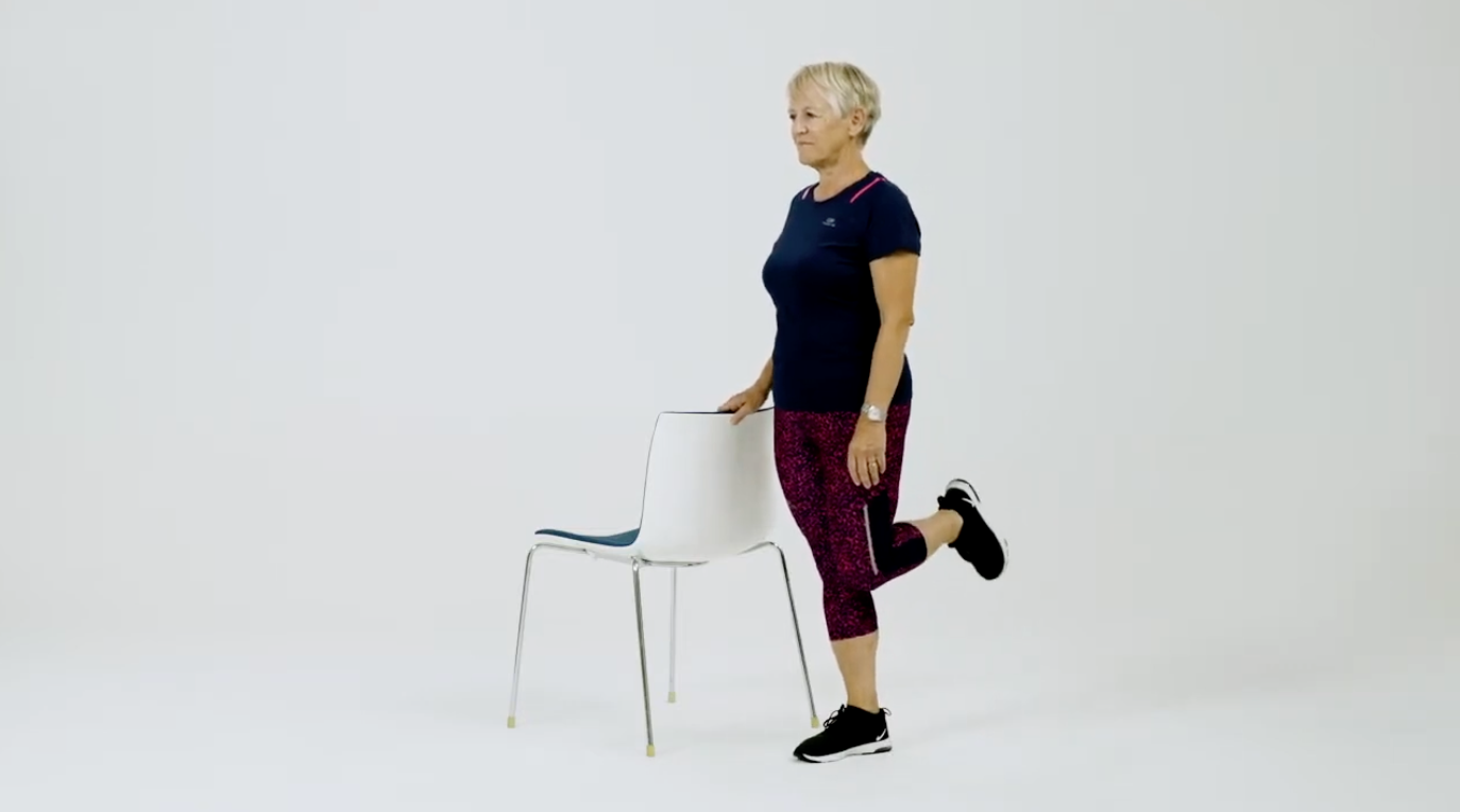 Eldre kvinne trener ved stol. Skjermdump fra treningsfilm