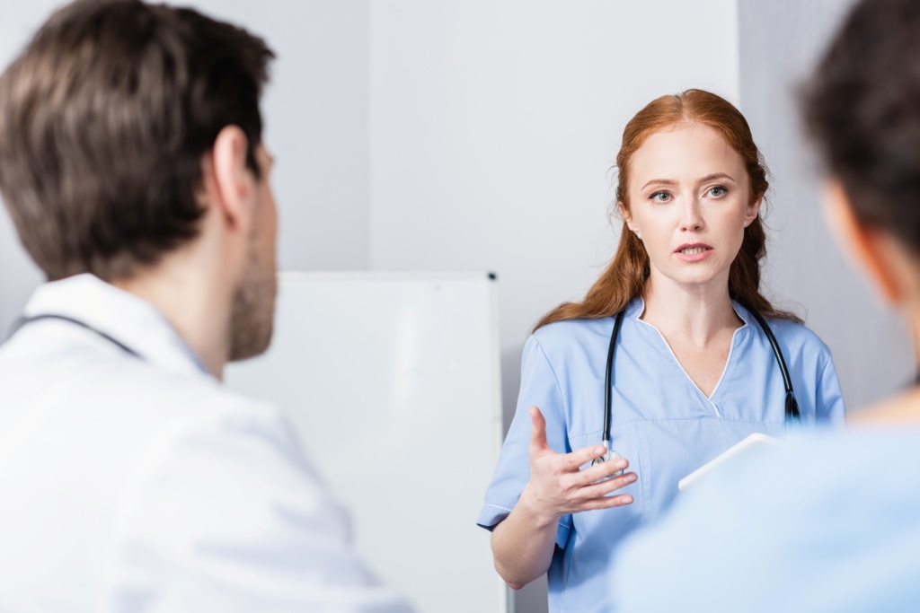 Ung sykepleier snakker med annet helsepersonell