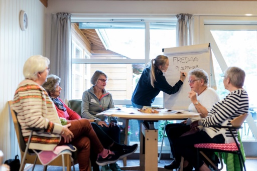 Helsepersonell skriver på tavle med eldre i gruppe. Foto