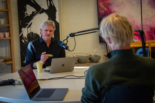 Mann ser på gammelost med annen mann i podkaststudio. Foto